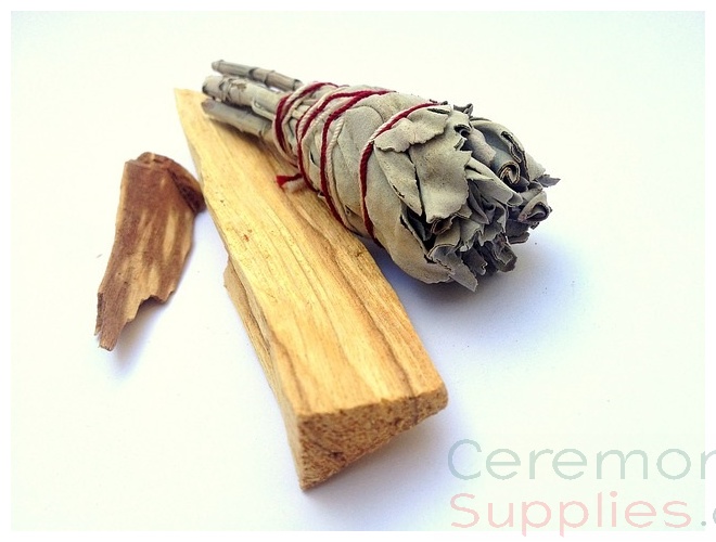 close up of dried sage with thin red string around it over a piece of pine wood