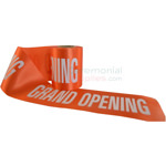 Orange ceremonial grand opening ribbon unraveled to show printed text.