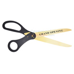 Golden printed scissors with black handles displaying grand opening message on blade.