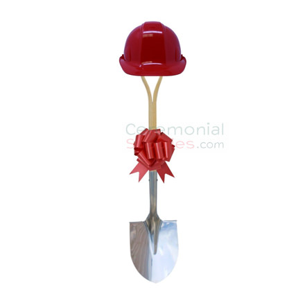 Upright view of red groundbreaking shovel, hard hat and bow kit.