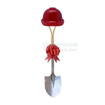 Upright view of red groundbreaking shovel, hard hat and bow kit.